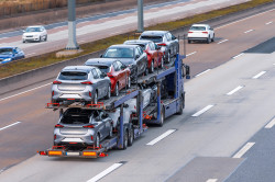 Transportation of new cars on a trailer with a truck for delivery to dealers.